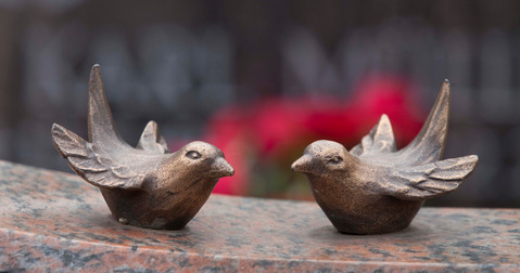 Skulpturen von zwei kleinen Vögeln auf dem Friedhofsgelände