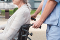 Eine Pflegekraft schiebt eine Frau in einem Rollstuhl