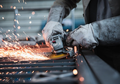 Ein Metallbauteil wird geschliffen. Dabei fliegen viele Funken.