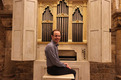 Auf dem Foto ist die Palmieri-Orgel im Bremer St. Petri Dom abgebildet. Davor auf der Orgelbank sitzt Domorganist Stephan Leuthold und blickt lächelnd in die Kamera.