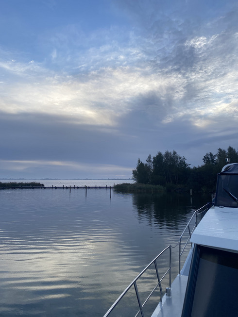 Ein Blick am Boot vorbei hinaus auf einen See während die Sonne aufgeht.