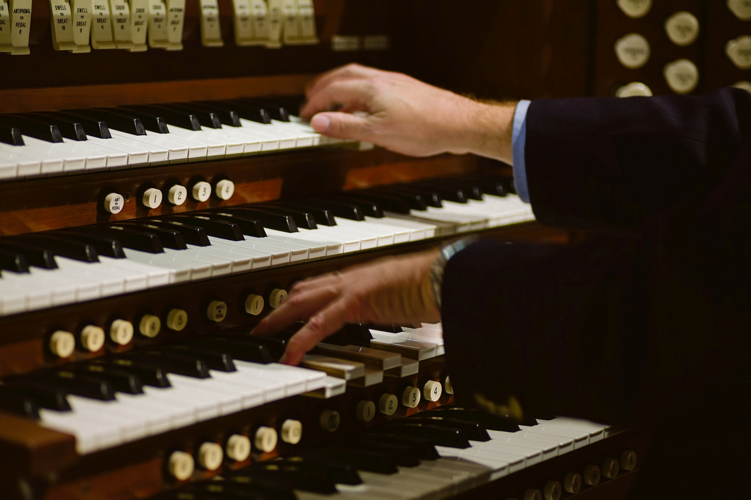 Hände spielen auf den Tastaturen einer Orgel