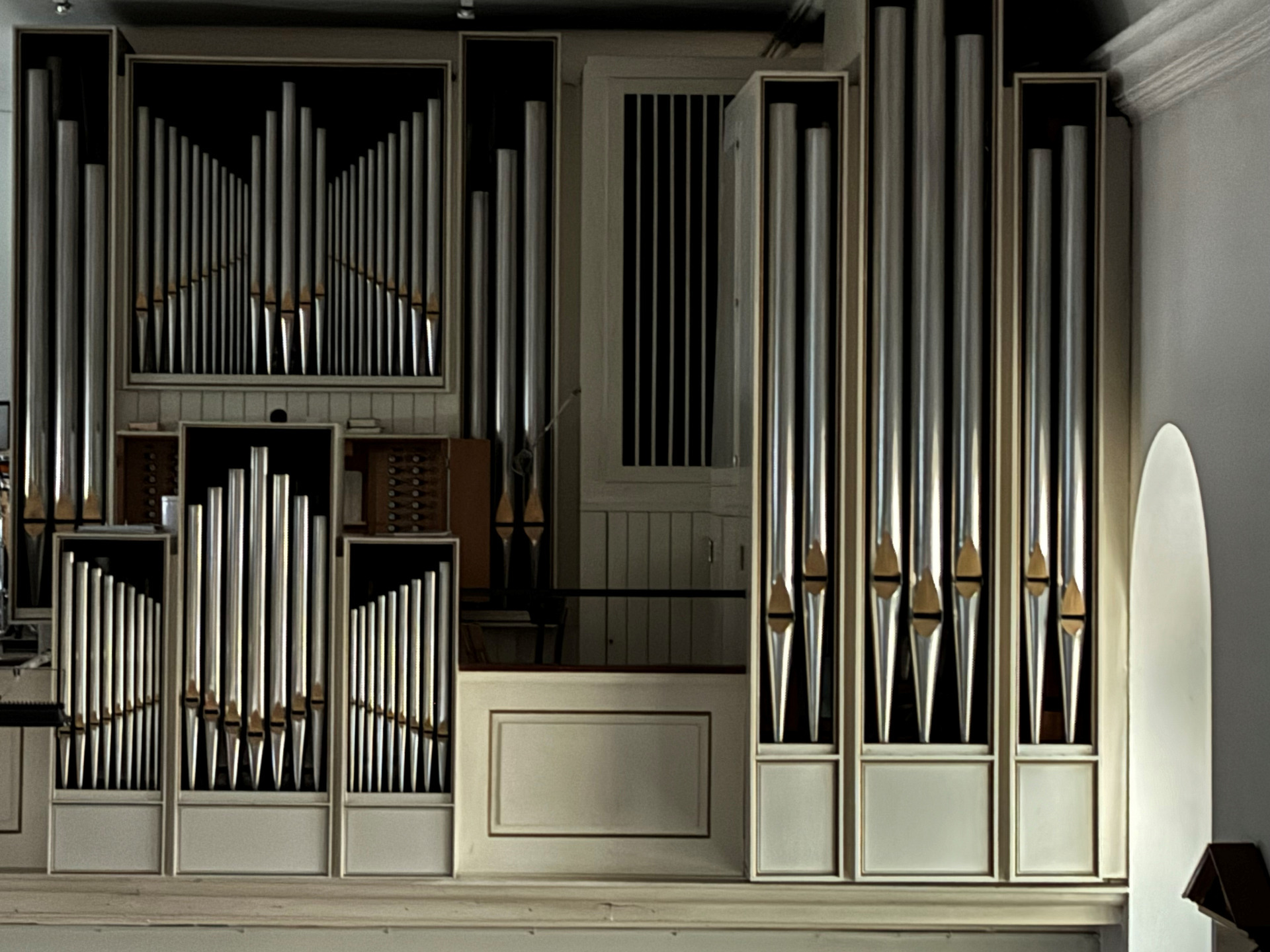 Die Abbildung zeigt eine Orgel mit zahlreichen Metallpfeifen in verschiedenen Größen. Die Pfeifen sind in Gruppen angeordnet und verleihen der Orgel ein beeindruckendes, symmetrisches Aussehen. Der Hintergrund ist schlicht und lässt die Orgel in den Vordergrund treten.
