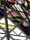 Ein farbenfrohes Kirchenfenster zeigt die Füße einer Figur, umgeben von geometrischen Mustern und Landschaftselementen. Die Szene vermittelt einen spirituellen Eindruck und ist reich an Details, die das Licht kreativ durch die bunten Gläser filtern.