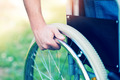 Eine Person hält ein Rad ihres Rollstuhls fest.