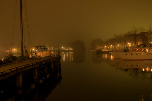 Ein Foto vom Hafen in Blokzijl bei Nacht. Es ist neblig und der Hafen ist von Lichtern gezäumt.