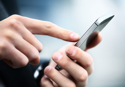 Das Foto zeigt eine Hand, die auf ein Handy tippt