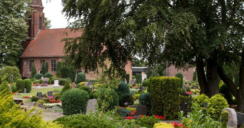 Die Kirche mit dem Friedhof und Bäumen.