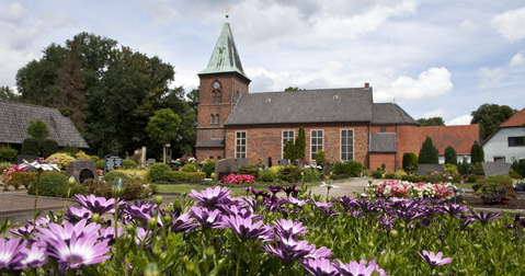 Die Kirche mit dem Friedhof und einigen Blumen.