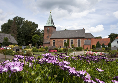 Die Kirche mit dem Friedhof und einigen Blumen.
