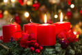 Ein Adventskranz aus Tannenzweigen mit 4 roten Kerzen. Der Kranz ist mit roten Schleifen geschmückt.