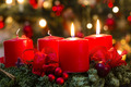 Ein Adventskranz aus Tannenzweigen mit 4 roten Kerzen. Der Kranz ist mit roten Schleifen geschmückt.
