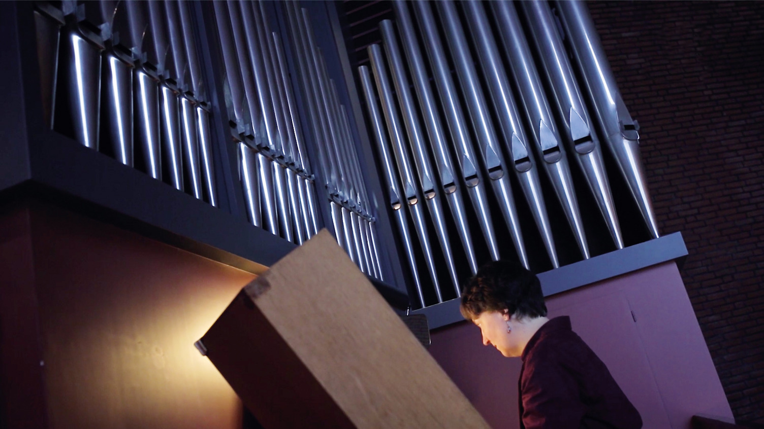 Kirchenmusikerin Ricarda Och spielt auf einer Orgel. Die Szene ist in stimmungsvoll ausgeleuchtet.