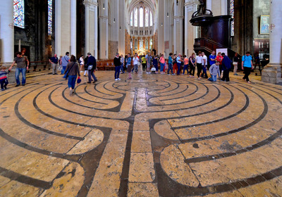 Das Foto zeigt das in den Boden eingelassene begehbare Labyrinth in der Kathedrale von Chartres mit zahlreichen Besuchern der Kirche.