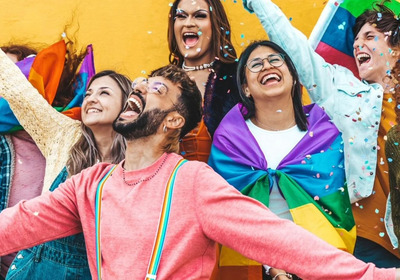 Fröhliche Menschen jubeln, z. T. in Regenbogenflagge gehüllt
