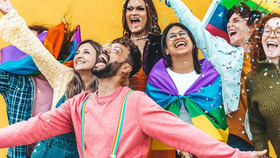 Fröhliche Menschen jubeln, z. T. in Regenbogenflagge gehüllt
