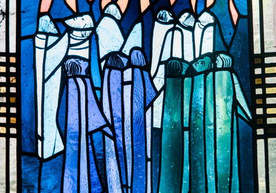 Ein Kirchenfenster in blauen Farbtönen. Es zeigt die Jünger Jesu mit Flammen über den Köpfen