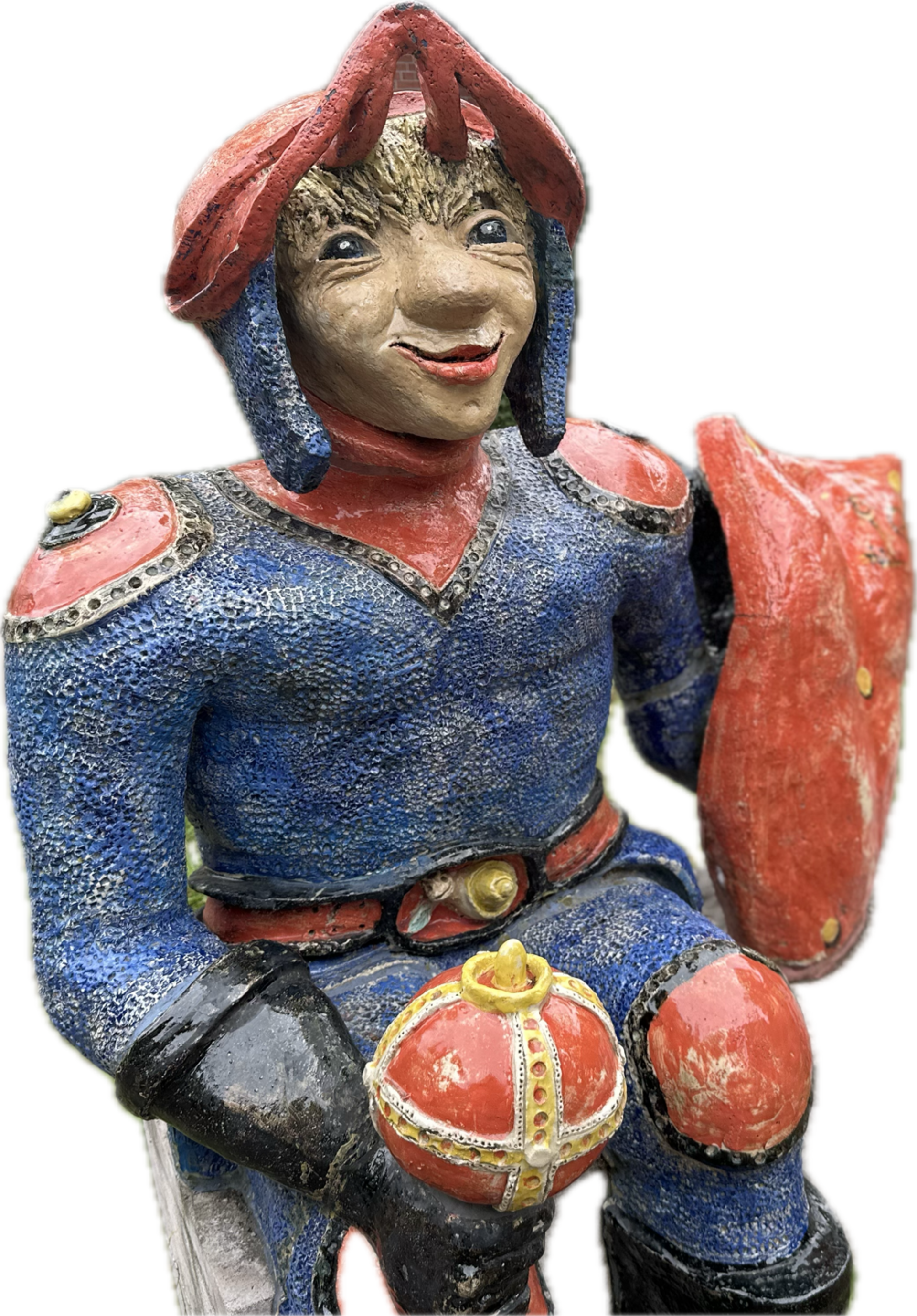 Eine farbenfrohe Figur eines Ritters in blauer und roter Kleidung, der lächelt. Er hält eine Krone in der linken Hand und hat ein Schild an seiner rechten Seite. Die Statue hat detailreiche Gesichtszüge und eine markante Kopfbedeckung.