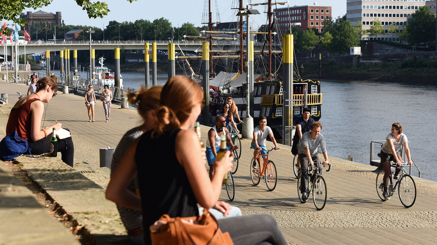 Personen erholen sich am Ufer der Weser in der Innenstadt