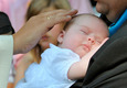 Das Foto zeigt einen schlafenden Säugling auf dem Arm seines Vaters bei der Taufe.