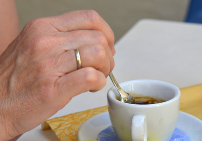 Eine Hand rührt mit einem Löffel den Kaffee in einer Tasse um