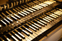 Die Abbildung zeigt eine Nahaufnahme von Tasten eines Musikinstruments, vermutlich einer Orgel oder einem Klavier. Die Tasten sind in verschiedenen hellen und dunklen Farbtönen angeordnet, wobei einige glänzende Details sichtbar sind. Die Bildkomposition hebt die feinen Strukturen der Tasten hervor.
