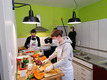 In einer freundlich gestalteten Küche wird ein Gemüsegericht vorbereitet, während ein Fernsehteam die Arbeiten filmt.