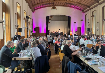 Das Foto zeigt das Plenum des Kirchentages an langen Tischen