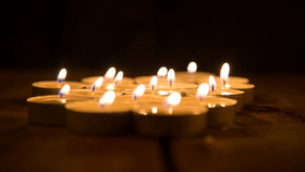 Mehrere kleine Kerzen leuchten, im Hintergrund ist es dunkel