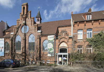 Backsteinkapelle umgeben von Wohnhäusern