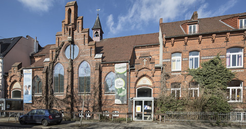 Backsteinkapelle umgeben von Wohnhäusern