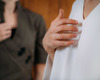 Zwei Personen stehen im Bild. Eine Frau trägt ein weißes Oberteil und legt ihre Hand auf die Brust. Die andere Person im Hintergrund trägt ein dunkles Oberteil und hat ebenfalls eine Hand auf der Brust. Die Atmosphäre wirkt ruhig und förderlich für eine harmonische Interaktion.