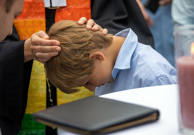 Ein Junge wird von einer Pfarrerin beim "Main Tauffest 2022" am Mainufer in Offenbach getauft.