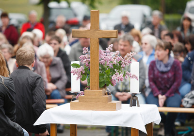 Ein Gottesdienst draußen, ein Kreuz steht im Vordergrund