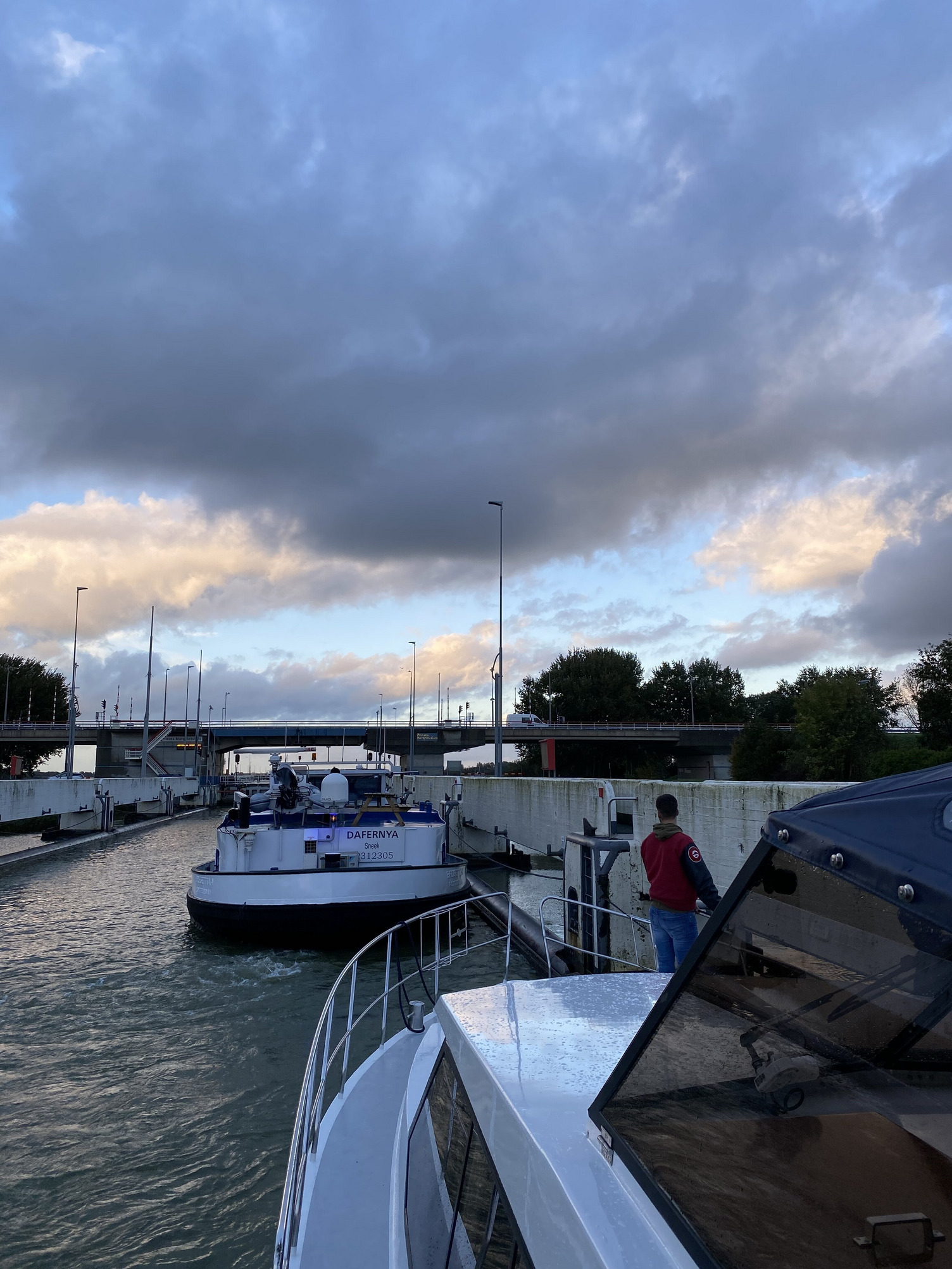 Der Blick an der Seite eines Bootes vorbei führt auf eine große Windschleuse, die sich das Boot mit einem großen Küstenmotorschiff teilt.