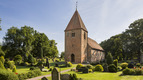 Kirche umgeben von einem Friedhof und Bäumen