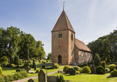Kirche umgeben von einem Friedhof und Bäumen