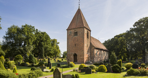 Kirche umgeben von einem Friedhof und Bäumen