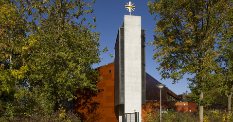 Kirchengebäude mit einem weißen Turm und goldenem Kreuz