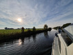 Zwei Boote unterwegs auf einem ruhigen Kanal an grünen Feldern vorbei.
