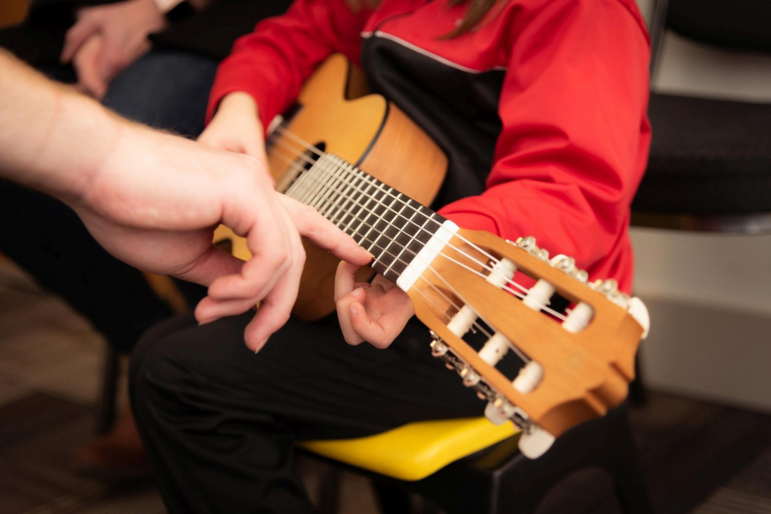 Einem Kind wird ein Gitarrengriff erklärt
