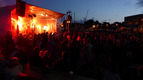 Eine Band spielt auf einer erleuchteten Bühne, davor die Silhouetten vieler Menschen