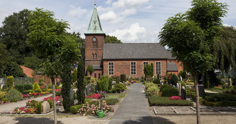 Kirchengebäude mit Friedhof und Bäumen