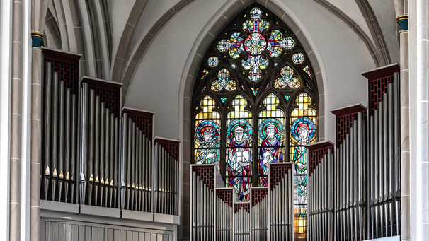Das Foto zeigt die Orgel in der Bremer Propsteikirche St. Johann. Im Hintergrund sieht man ein buntes Glasfenster