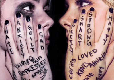Das Foto zeigt zwei weibliche Gesichter, die ihre Wangen mit ihren tätowierten Händen umfassen. Zu lesen sind Worte wie Krieg, Hass, Liebe oder Depression. Das künstlerische Foto soll Empfindungen angesichts von Gewalterfahrungen zum Ausdruck bringen.