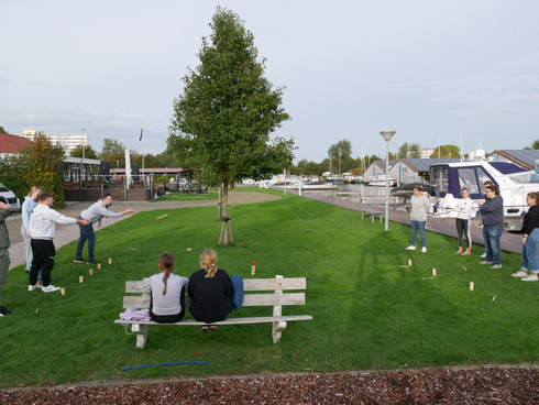 Eine Gruppe Menschen spielt auf einer Wiese im Hafen das Spiel Wikingerschach.