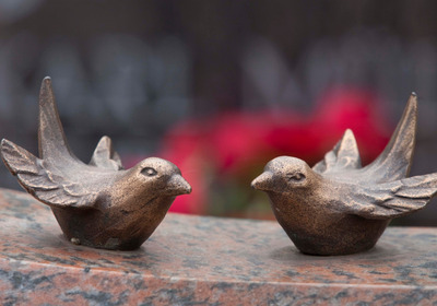 Skulpturen von zwei kleinen Vögeln auf dem Friedhofsgelände