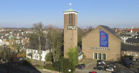Kirchgebäude mit freistehendem Kirchturm im Stadtgebiet.