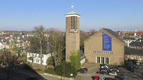 Kirchgebäude mit freistehendem Kirchturm im Stadtgebiet.