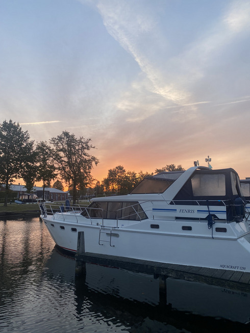 Ein Boot liegt im Hafen und dahinter geht die Sonne auf.